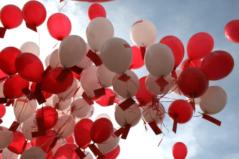 large group of white and red balloons with a blue sky in the background