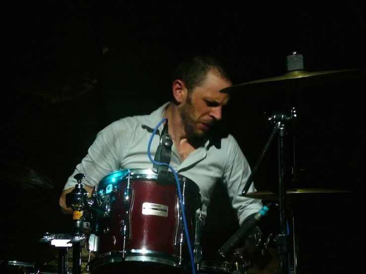 a drummer is shown performing with a dark background