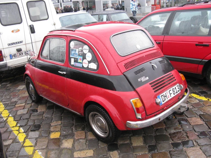 a small red car parked next to a white van