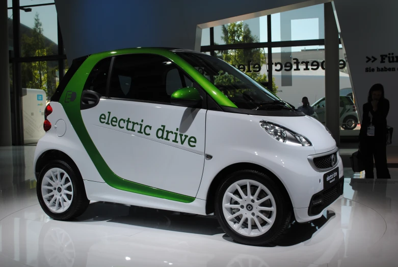 a small white electric drive car parked in front of a building