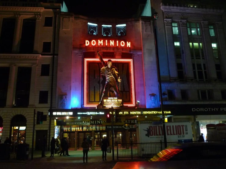 a lighted sign for dominion in front of buildings