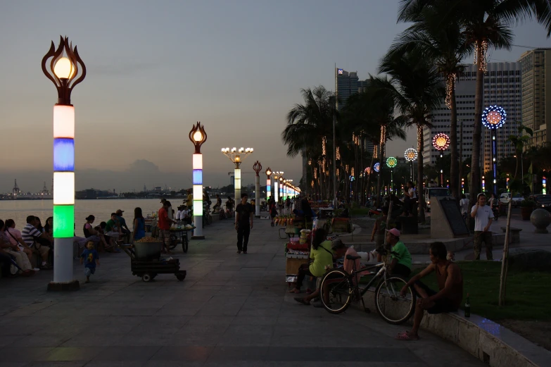 the people are sitting next to the waterfront at night