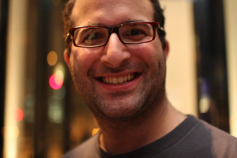 a close up of a man wearing glasses smiling at the camera