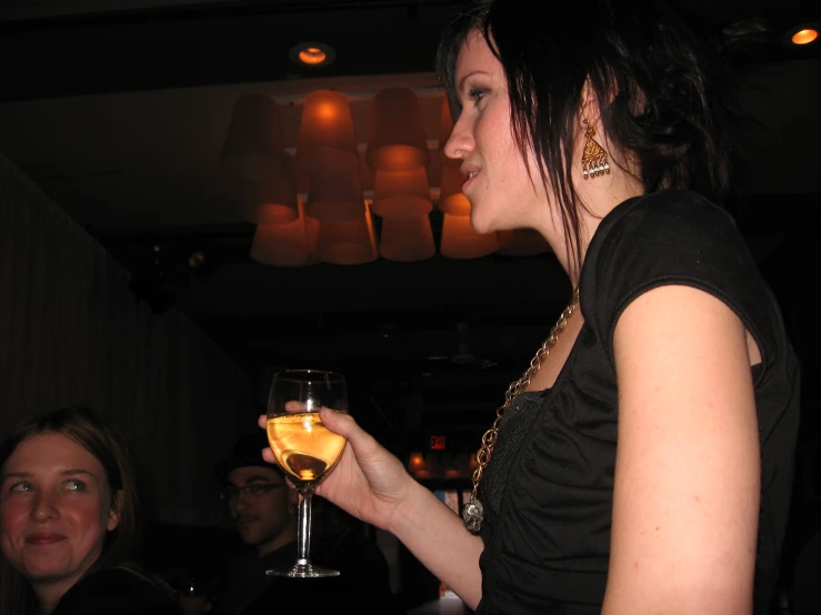 a woman is holding a glass with orange liquid in it