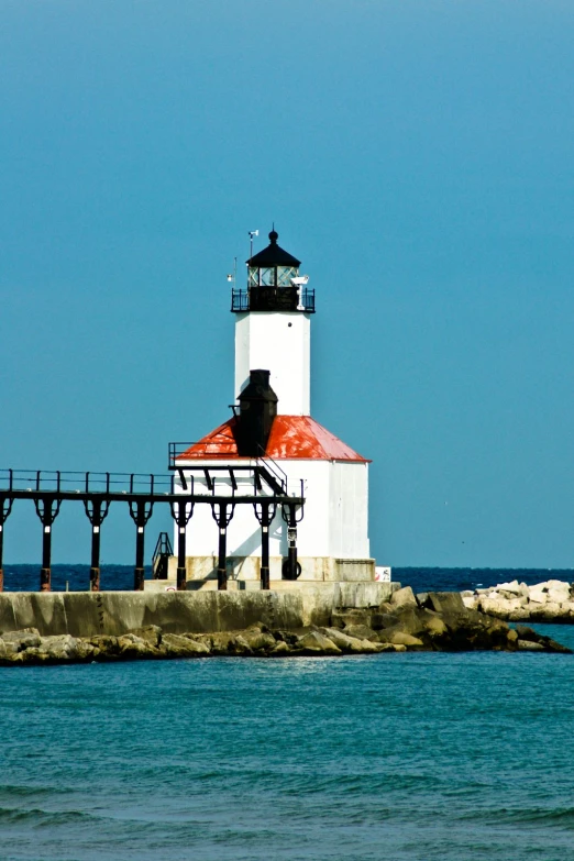 a white light house sitting in the middle of the ocean