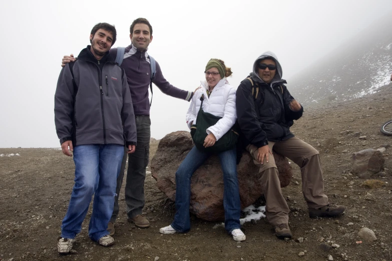 four people are smiling for a picture near some rocks