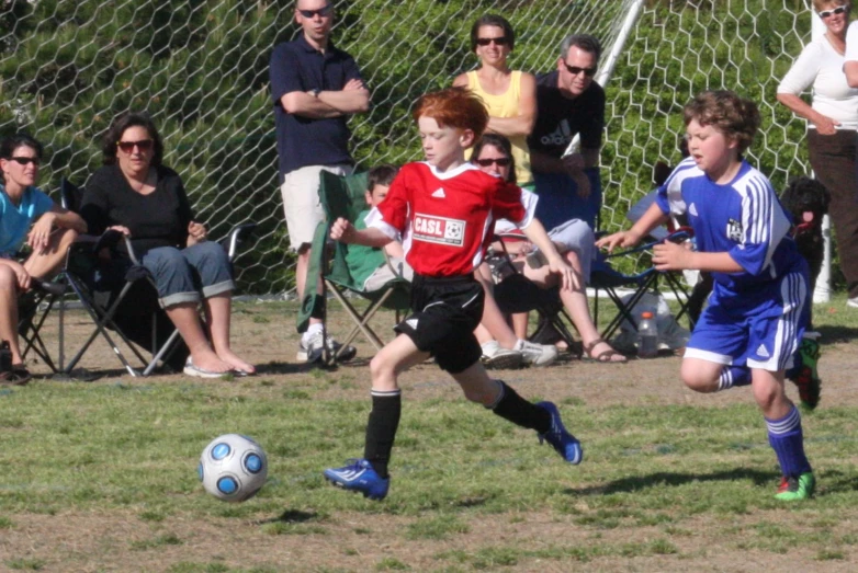 a little boy running after a soccer ball