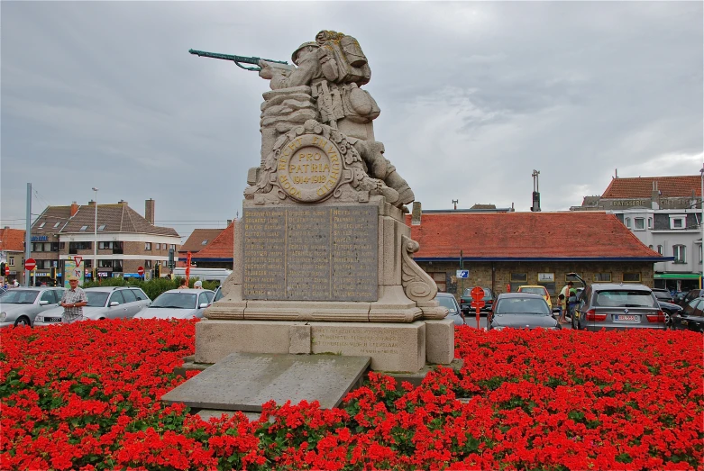statue in middle of garden with red flowers on it