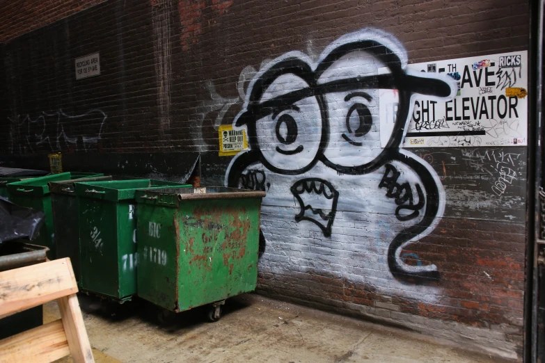 a garbage can is near a graffitied wall
