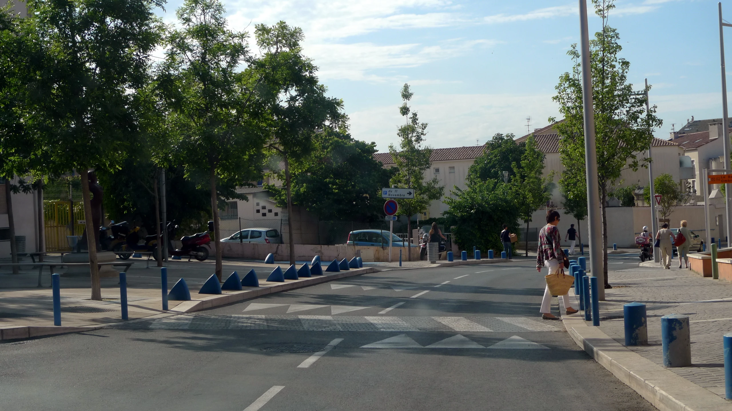 a woman with a tan suitcase stands at the end of a street with blue barricades