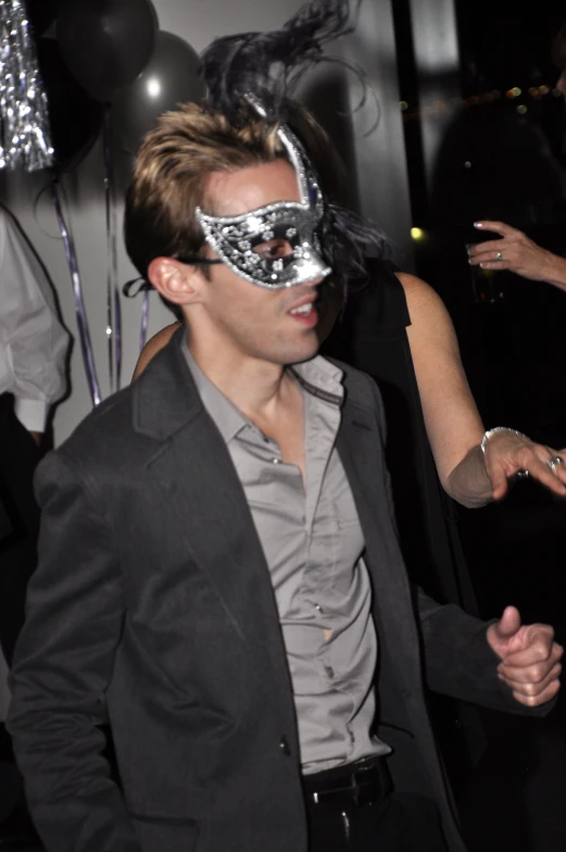 the man is wearing a silver masquerade