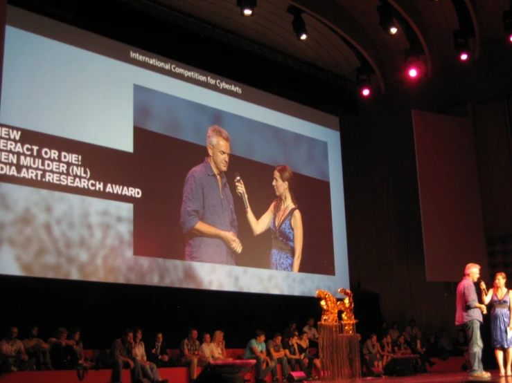 people on stage talking with an audience looking on