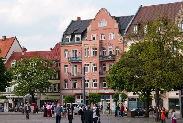 people walking around town square with a building in the background