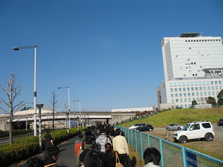 people walk down the sidewalk in a city with tall buildings