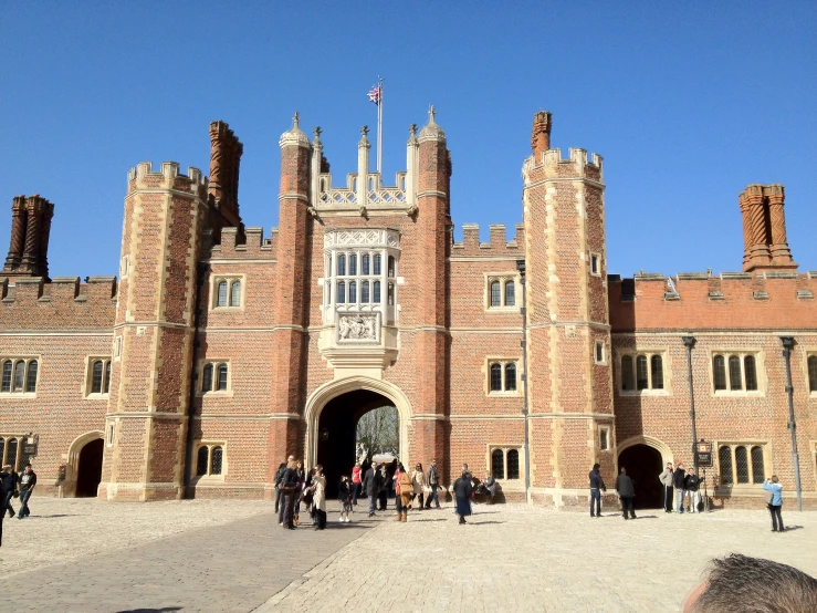 people walking towards a tall brick castle like building