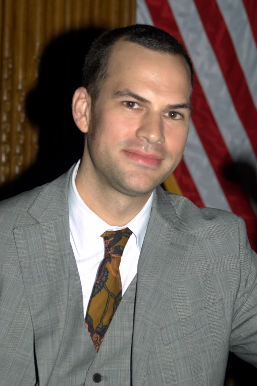 a man in a gray suit is smiling for the camera