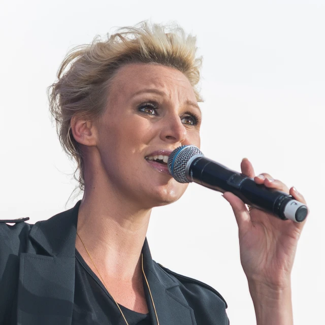 woman with blond hair singing into a microphone