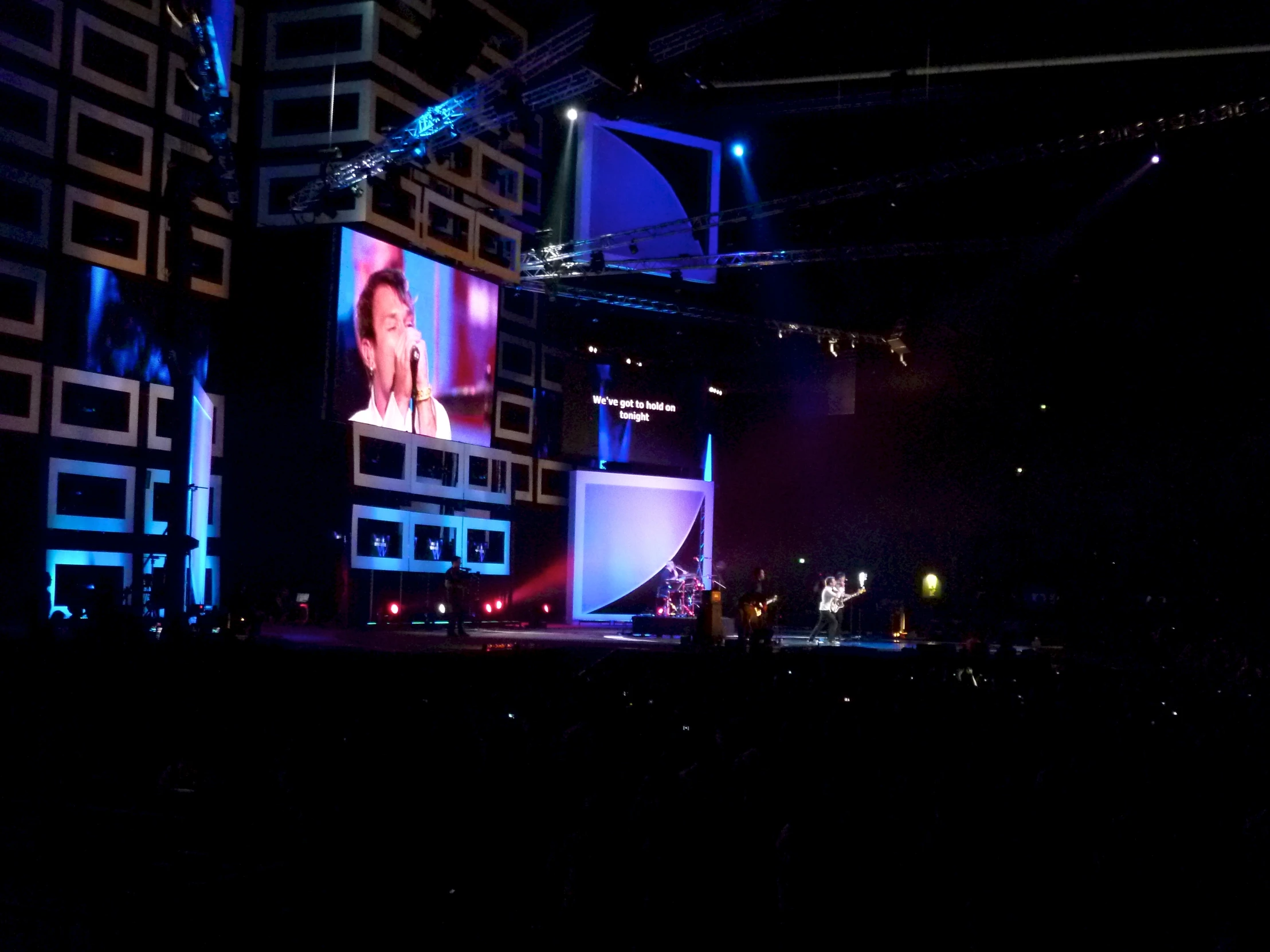 people standing on stage in front of large screens and lighting