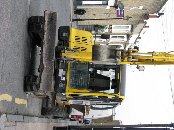 a small yellow crane sitting on the street next to a truck