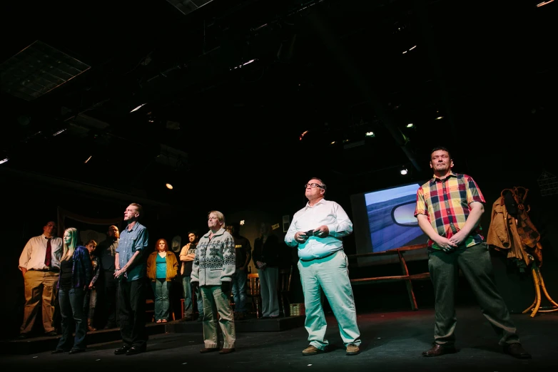 a group of people standing on a stage while someone speaks on the phone