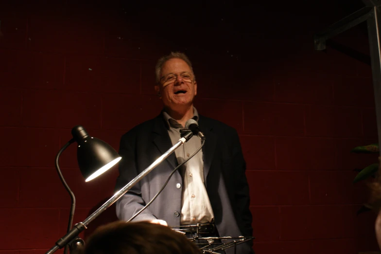 an old man is singing at a microphone