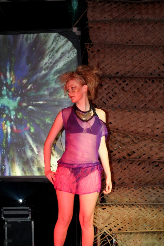 a woman in a purple and pink dress standing on a stage with a speaker