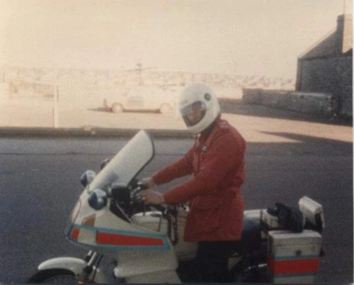 a man wearing a white helmet and jacket riding on a motorcycle