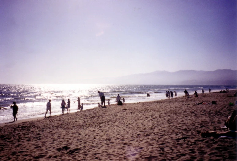 group of people walk on the beach while others walk in the ocean