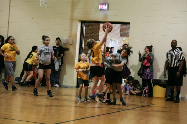 children playing basketball at an indoor school gym