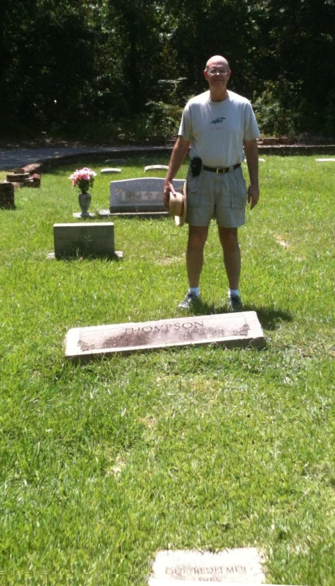 an elderly man standing in the grass near graves