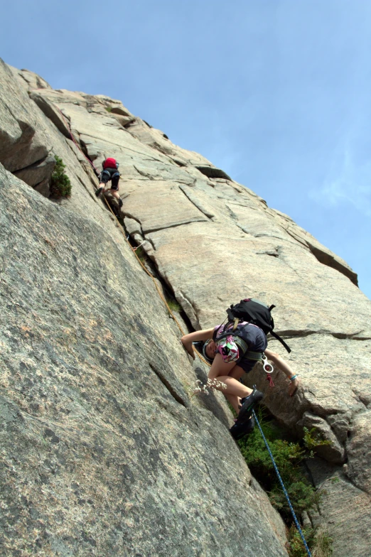 two people climbing up a rocky mountain in the wilderness