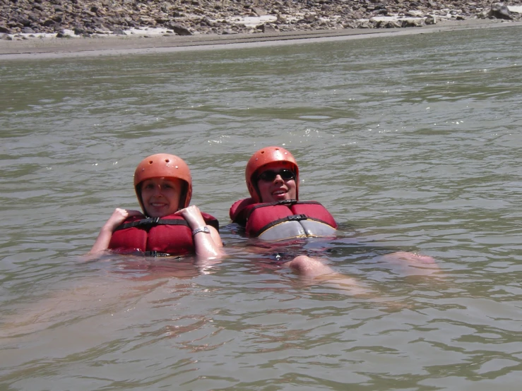 two people wearing life jackets are floating on rafts