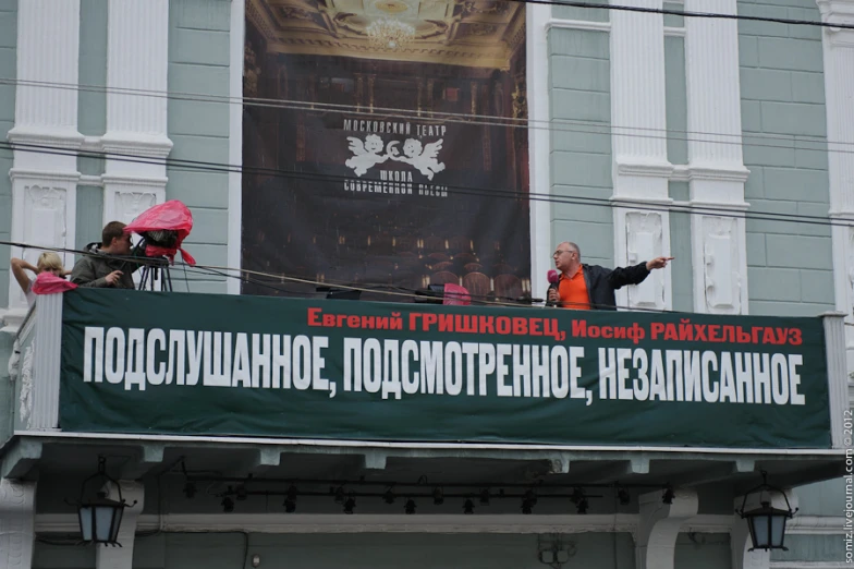 a man waving and holding an umbrella is seen from the top balcony