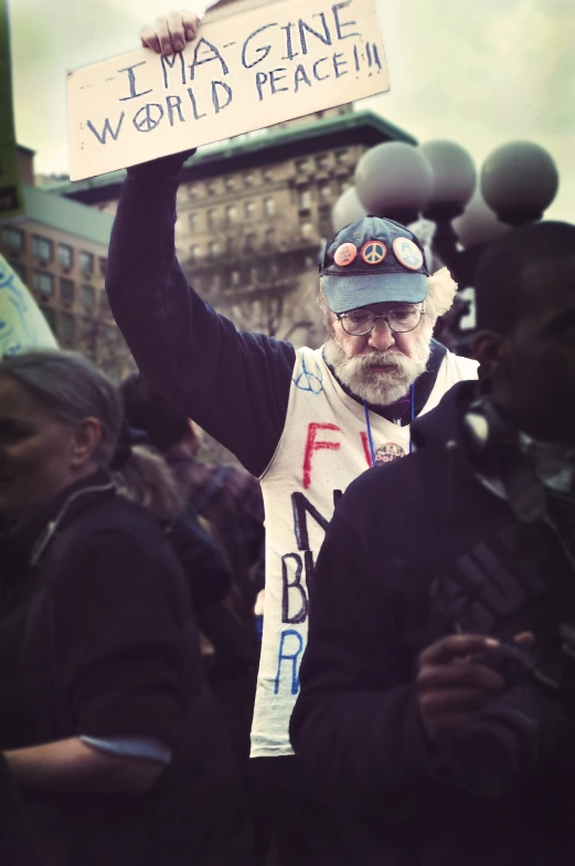 a man with a sign with words on it holding two microphones in his hands