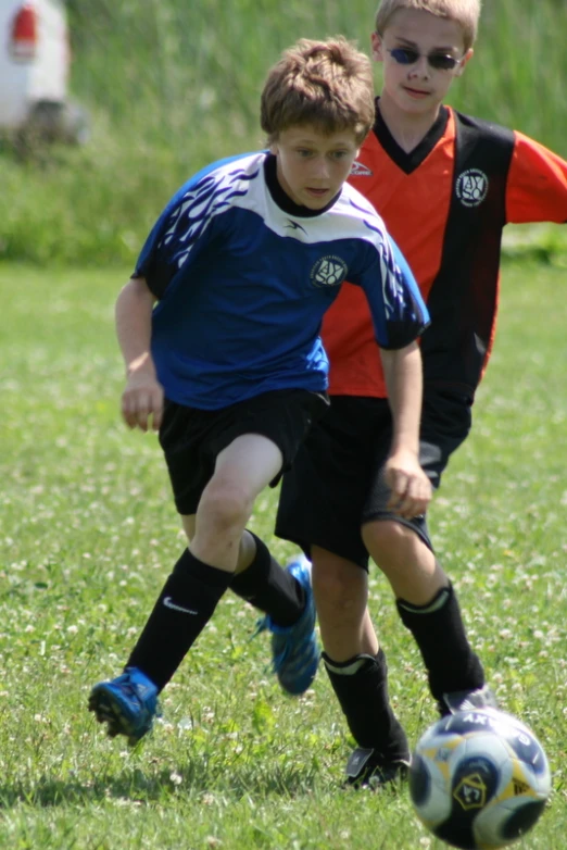 two little boys who are kicking a soccer ball