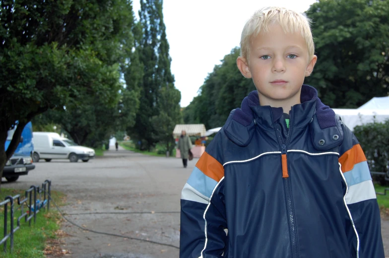 a boy is standing in the street near a park