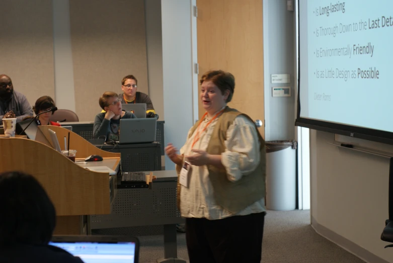 a woman standing in front of a crowd at a presentation