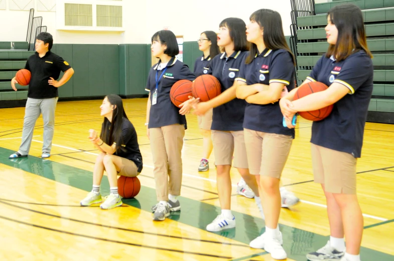 there are young people standing in a gym with a basketball