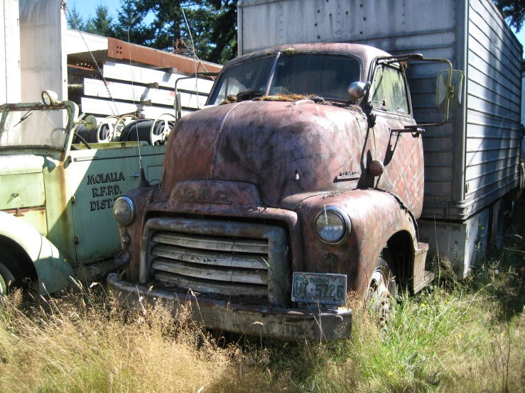 an old, rusted truck is parked next to a metal structure