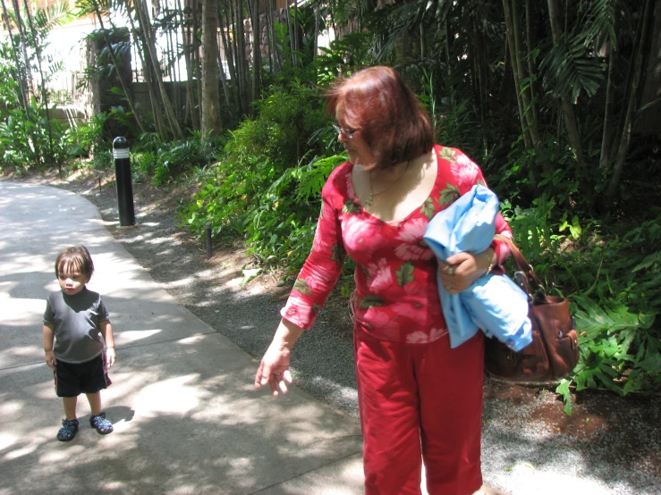 the lady with red hair is walking beside the little boy