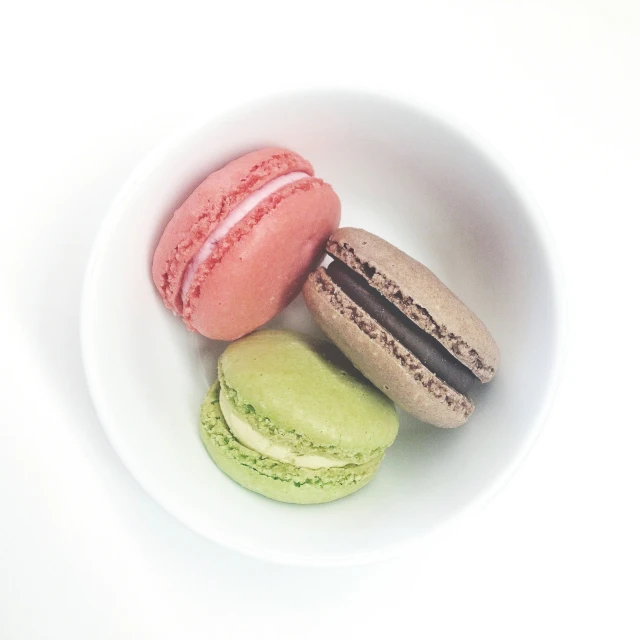 a white bowl of macaroons on a table