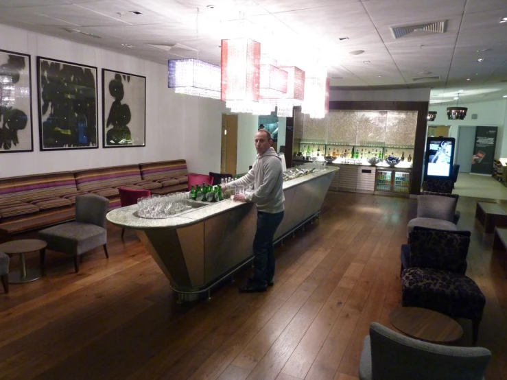 a man in a restaurant behind a bar with bottles on it