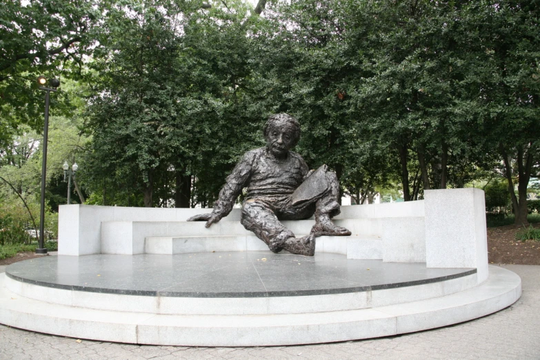 a statue in a park is sitting on a bench