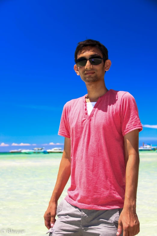 the young man is standing in shallow water on the beach