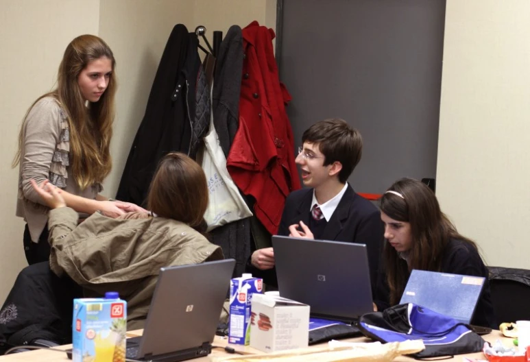 several young adults sitting at tables with their laptops