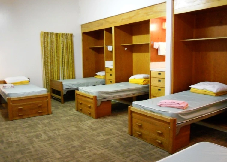 a room with some beds a cupboards and drawers