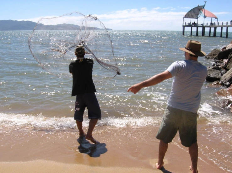 a man throws a net while another watches