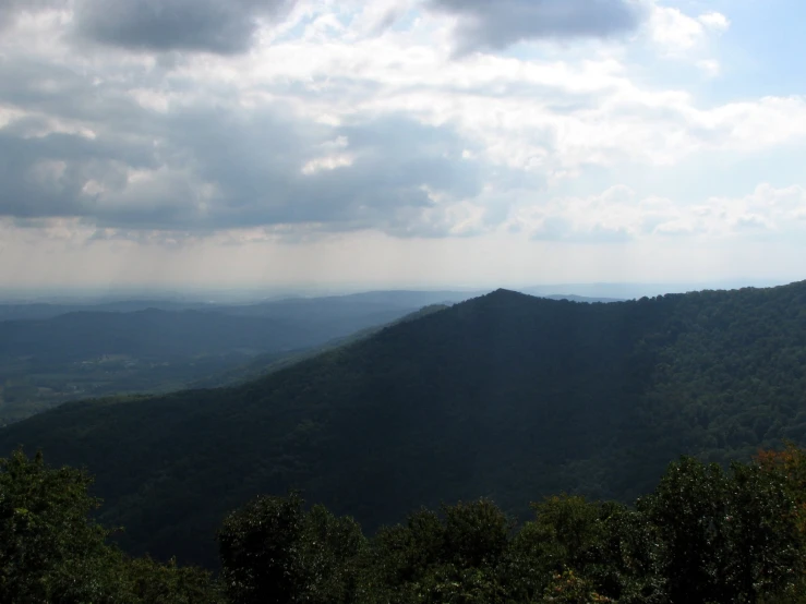 the sky is very dark and there are some clouds over a mountain range