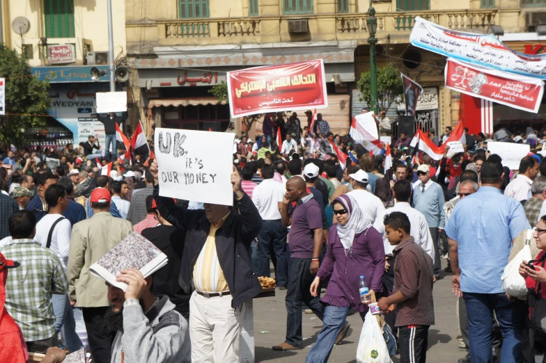 group of people walking in the street while holding protest signs