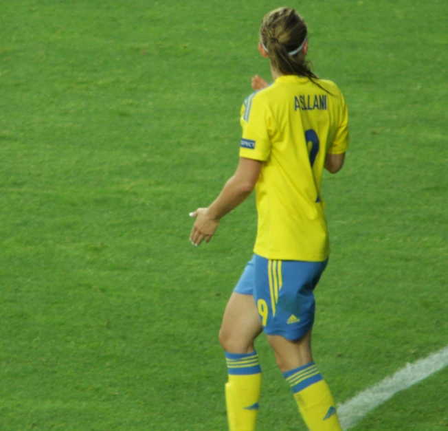 a soccer player is standing on a field and holding a ball